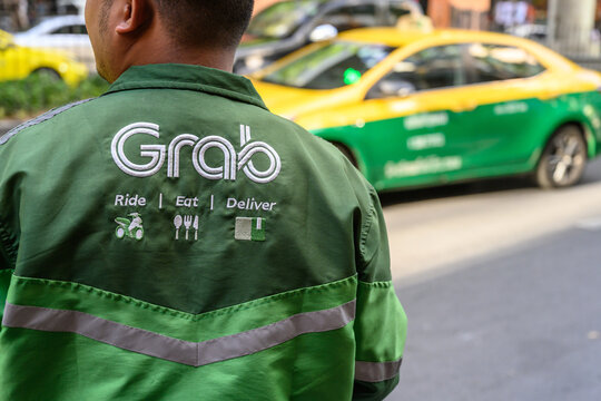 .Ride, Eat, Deliver, the Grab food delivery service logo displayed on the shirt of a Grab delivery rider in Bangkok, Thailand, Asia