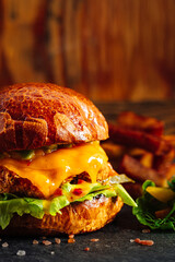 Fresh craft burger on a rustic wooden background. French fries on the side 