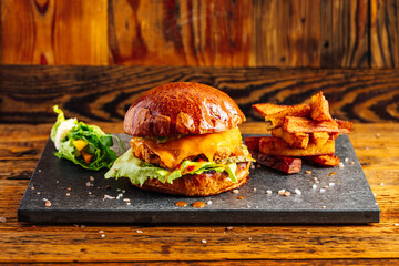 Fresh craft burger on a rustic wooden background. French fries on the side 