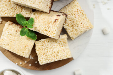 Delicious puffed rice bars and mint on white wooden table, top view