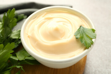 Delicious mayonnaise sauce in bowl with parsley on table, closeup