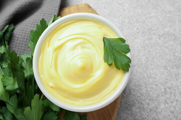 Delicious mayonnaise sauce in bowl with parsley on grey table, top view