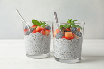 Delicious chia pudding with strawberries, blueberries and mint in glasses on white wooden table