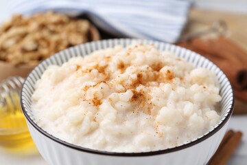 Tasty rice pudding with cinnamon on table, closeup