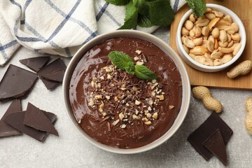 Delicious chocolate mousse in bowl and ingredients on grey table, flat lay