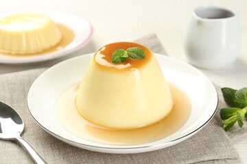 Delicious pudding with caramel sauce and mint served on table, closeup