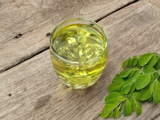 Moringa tea leaves (moringa oleifera) in glass on wooden table background, healthy drink lifestyle 