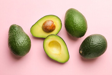 Whole and cut avocados on pink background, flat lay