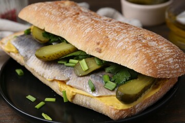 Tasty sandwich with herring, pickles, green onions and parsley on table, closeup