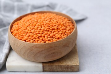 Red lentils in bowl on light table, closeup