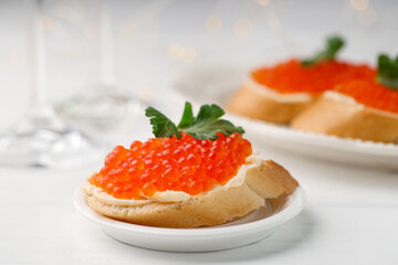 Tasty sandwiches with red caviar on white wooden table, closeup