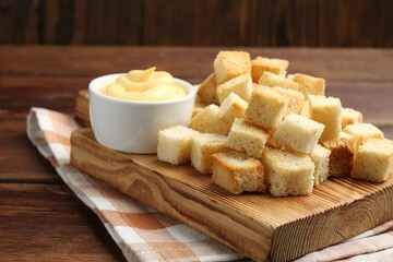 Delicious crispy croutons with sauce on wooden table. Space for text