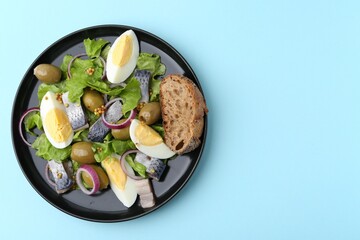 Delicious salad with herring, egg, mustard and vegetables on light blue background, top view. Space for text