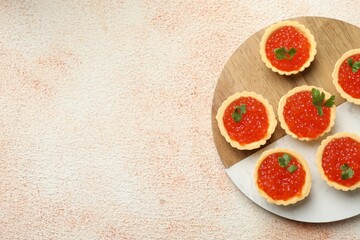 Tartlets with red caviar and parsley on beige background, top view. Space for text