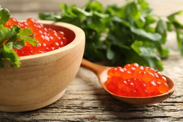 Red caviar and parsley on wooden table, closeup