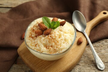 Delicious rice pudding with cinnamon, almonds and mint served on wooden table, closeup