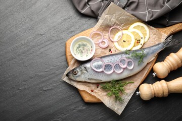 Tasty herring with spices on black table, flat lay. Space for text