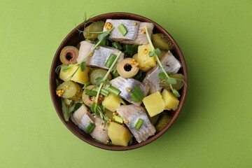 Delicious salad with herring on green background, top view