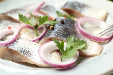 Pieces of delicious herring with spices and onions on plate, closeup
