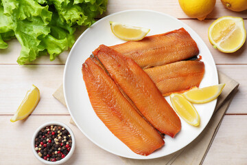 Delicious smoked herring fillets with lemon slices on white wooden table, flat lay