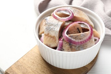 Pieces of delicious herring with onions on white table, closeup