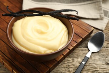 Tasty vanilla pudding and pods served on wooden table, closeup