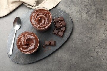 Tasty pudding and pieces of chocolate on grey table, flat lay. Space for text