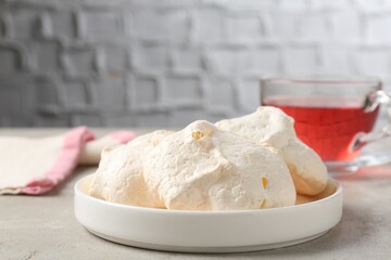 Delicious homemade meringue cookies and tea on gray table, closeup