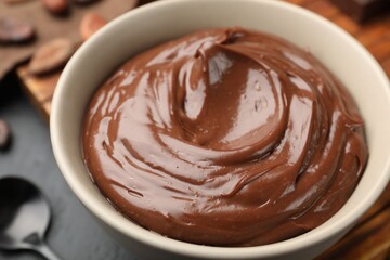 Tasty chocolate pudding in bowl on black table, closeup