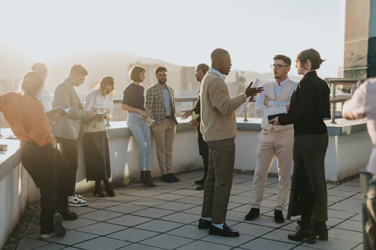 A group of business colleagues engage in a brainstorming session on a high-rise balcony, fostering teamwork and innovative solutions under the warm sunlight. A setting for creative ideas and