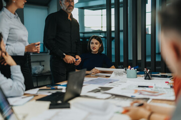 A diverse group of business colleagues engage in a brainstorming session to develop innovative ideas. The team includes individuals of different ages and backgrounds, highlighting teamwork.