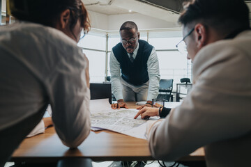 A group of business professionals collaborate in a modern office setting, discussing strategies and solutions. The image captures teamwork, analysis, and focused engagement in a corporate environment.