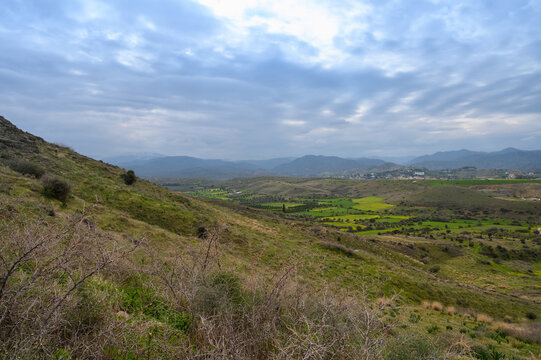 Exploring the serene hill landscapes with sprawling green fields and distant mountains under a cloudy sky