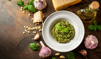 basilikum pesto in einem runden Teller auf einem Holztisch,  mit Parmesan, Knoblauch und Pinienkernen