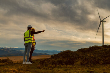 Engineers discussing next steps in wind turbine installation project in mountainous landscape at...