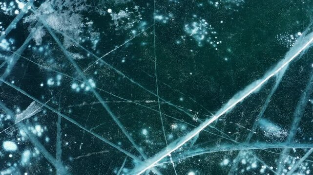 Aerial top view of frozen Lake Baikal. Blue transparent clear smooth ice with deep cracks. Famous natural landmark of Russia, 4k