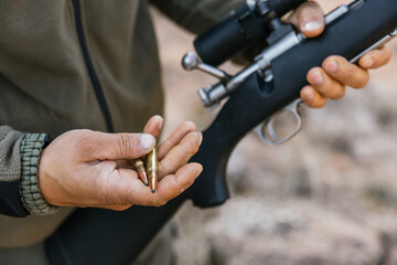 Hunter holding rifle and bullets getting ready for the hunt