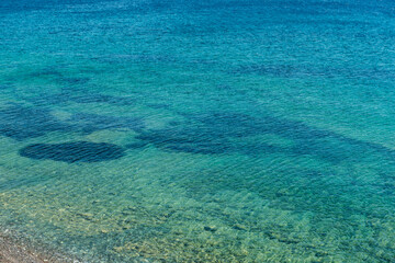Obraz premium Pebble coast and waves in Datca, Turkey. Clear water of the Mediterranean coast of Turkey.
