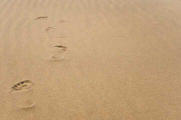 Human footprints of bare feet in the dry sand, footpath