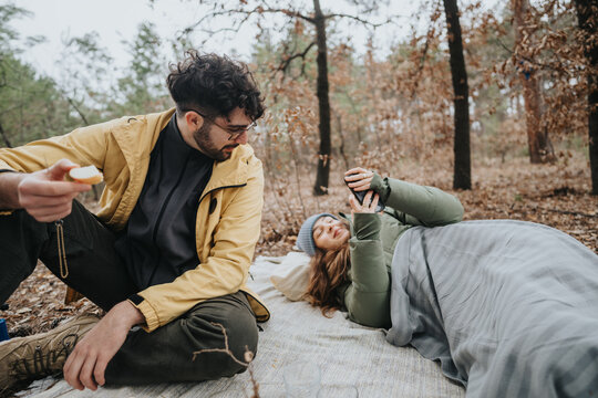 Two friends spending quality time in an autumn forest, chatting and unwinding together. Emphasizes outdoor leisure, camaraderie, and the beauty of nature in a serene woodland setting during fall.