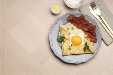 Delicious crepe with egg, bacon and green peas served on wooden table, flat lay. Space for text
