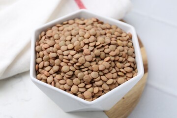 Raw brown lentils on white table, closeup