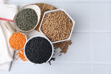 Different types of lentils on white tiled table, top view. Space for text
