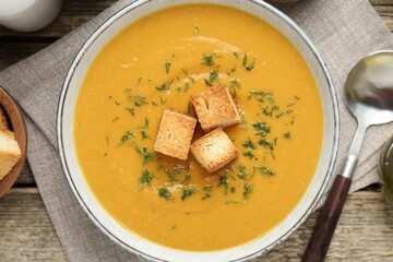 Delicious lentil cream soup served on wooden table, flat lay