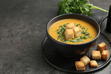 Delicious lentil cream soup served with croutons on grey table, closeup. Space for text