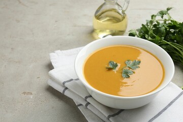 Delicious lentil cream soup with parsley and oil on light grey table, closeup. Space for text