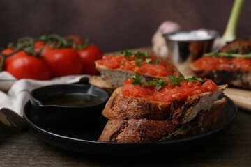 Tasty bread with tomatoes, parsley and oil on wooden table, closeup