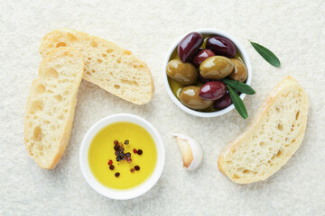 Slices of bread with oil, spices and olives on light table, flat lay
