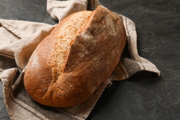 Fresh loaf of bread on black table, closeup. Space for text