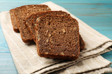 Pieces of fresh bread on light blue wooden table, closeup